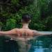 Androgynous person with tattoos bathing in a natural body of water