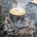 Birch tar being cooked down in a tin over a campfire
