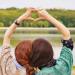 Friends make a heart shape with their hands overhead.