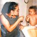 A mother shows her toddler how t brush teeth.