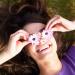 A girl holds daisies over her eyes representing positivity