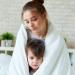 A mother holds her child inside a white blanket representing Safe Blend