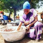 A woman stirs and kneads by hand a bowl of shea nut paste to make shea butter.