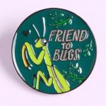 An enamel pin of a praying mantis says Friend To Bugs