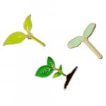 Three enamel pins of seedlings